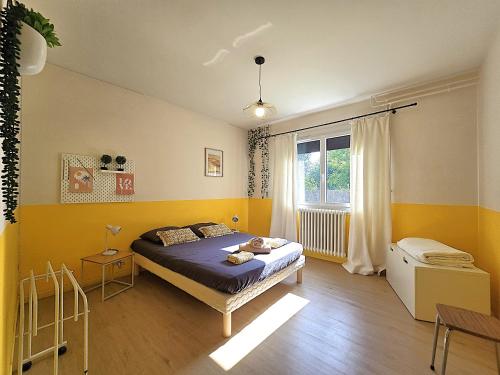 une chambre avec un lit aux murs jaunes et une fenêtre dans l'établissement Belle villa au bord du canal - Piscine, jardin et bois -14 personnes - 6 chambres - 5 minutes de la gare - Terrasses et pergola - Parking gratuit, à Montauban