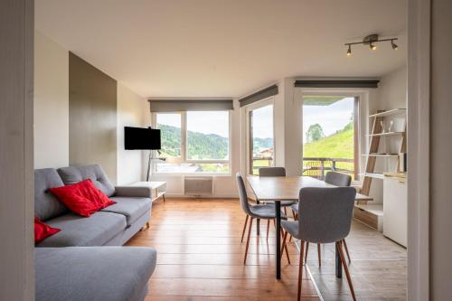un salon avec un canapé et une table avec des chaises dans l'établissement La Belle Evasion - proche station de ski, aux Gets