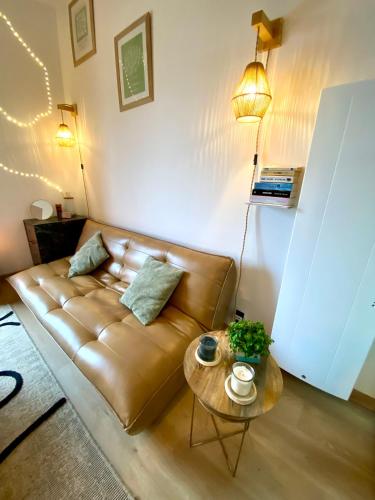 a living room with a brown leather couch and a table at Maison romantique avec Balnéo Duo in La Bernerie-en-Retz