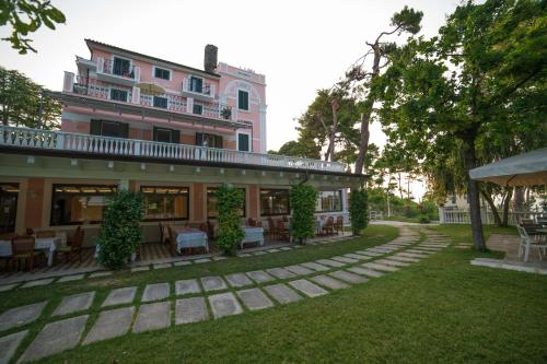 a pink building with tables and chairs in a yard at Park Hotel Villa Maria in San Menaio