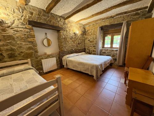 a bedroom with two beds in a stone building at Agroturismo Gure Naia in Carranza