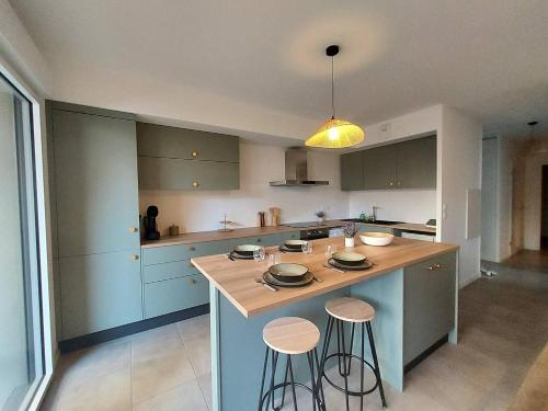 une cuisine avec des placards bleus et un îlot avec des tabourets dans l'établissement Joli 3 pièces à la plage Sud de Vieux-Boucau, à Vieux-Boucau-les-Bains