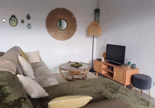Il comprend un salon doté d'un canapé et d'une table avec une télévision. dans l'établissement Joli 3 pièces à la plage Sud de Vieux-Boucau, à Vieux-Boucau-les-Bains