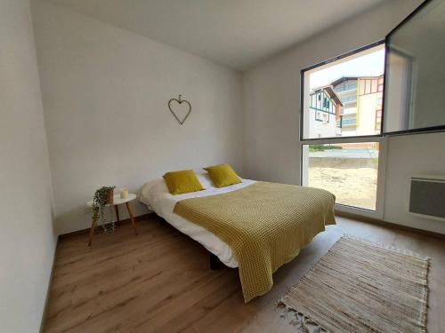 une chambre avec un lit avec des oreillers jaunes et une fenêtre dans l'établissement Joli 3 pièces à la plage Sud de Vieux-Boucau, à Vieux-Boucau-les-Bains
