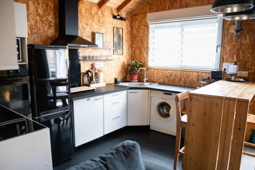 une cuisine avec des armoires blanches et une laveuse et une sécheuse dans l'établissement Les Caravelles chalets de Tarbes, à Tarbes