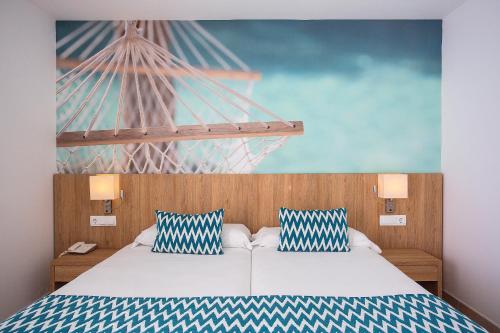 a bedroom with a bed with two blue and white pillows at BQ Sarah -Adults Only in Can Picafort