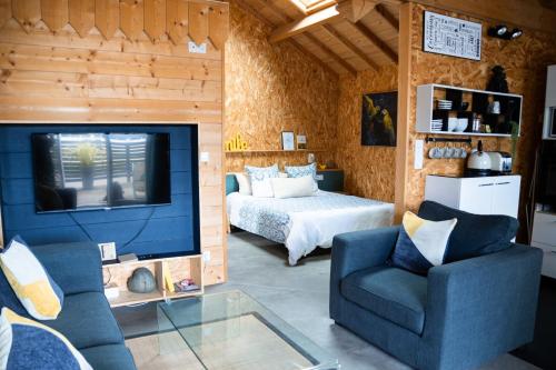 un salon avec une télévision et un lit dans l'établissement Les Caravelles chalets de Tarbes, à Tarbes