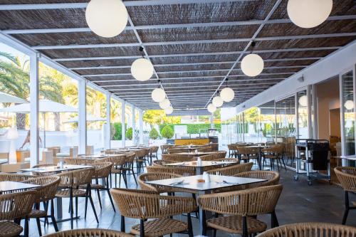 a restaurant with tables and chairs and windows at BQ Sarah -Adults Only in Can Picafort