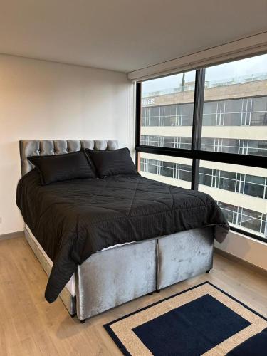 a bedroom with a large bed and a large window at Roger USAQUEN 120 in Bogotá