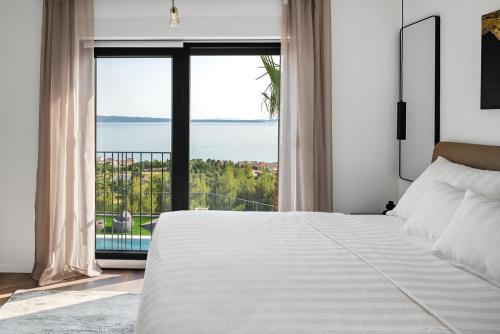 sypialnia z dużym białym łóżkiem i dużym oknem w obiekcie NEW! Villa El Capitano Private Seaview Retreat Near Split w Podstranie
