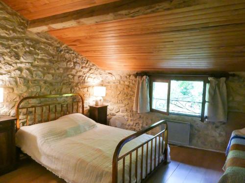 une chambre avec un lit et un mur en pierre dans l'établissement Maison de charme sous le soleil de la Drôme, à Châtillon-en-Diois