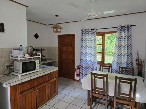 una cucina con forno a microonde e tavolo con sedie di La Digue Ylang Ylang a La Digue