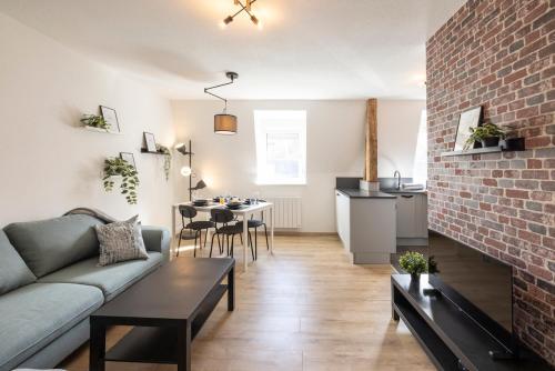 un salon avec un canapé et un mur de briques dans l'établissement MonSéjourCosy - L'Urban - Cosy - Netflix, à Mulhouse