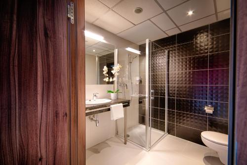a bathroom with a shower and a toilet and a sink at Focus Hotel Premium Gdańsk in Gdańsk