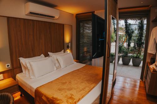 a bedroom with a large bed with white pillows at Duke Beach Hotel Maresias in Maresias