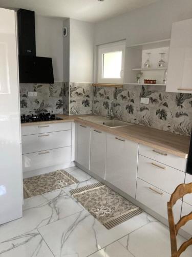 - une cuisine avec des placards blancs et un sol en marbre dans l'établissement Charming quiet house, à La Vernelle