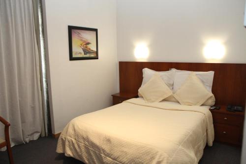 Habitación de hotel con cama con sábanas blancas en Hotel Solar dos Pachecos, en Lamego