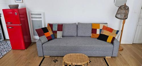 - un salon avec un canapé gris et des oreillers colorés dans l'établissement Evasion ensoleillée à St Jean de Luz Studio coquet avec balcon, à Saint-Jean-de-Luz
