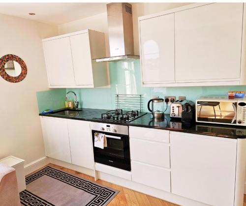 ブリクサムにあるBoutique Apartment Brixhamの白いキャビネットと黒いカウンタートップを備えたキッチン