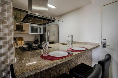 a kitchen with two plates and glasses on a counter at Flat c/ Limpeza Diária | Piscina e Praia - DL1804 in Recife