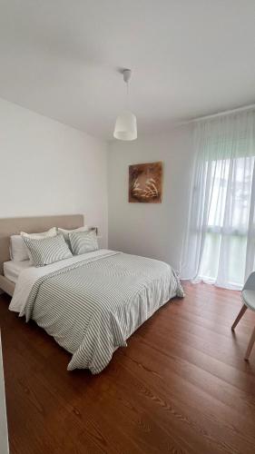 a white bedroom with a bed and a wooden floor at City Center House - Azure Waters in Ribeira Grande