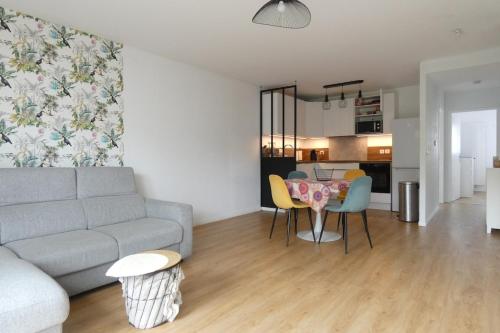 un salon avec un canapé et une table avec des chaises dans l'établissement Appart terrasse privée parking proche mer, à Pornichet