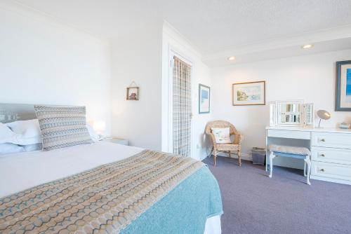 ein Schlafzimmer mit einem Bett, einem Schreibtisch und einem Stuhl in der Unterkunft 5 Mariners Reach in Saundersfoot