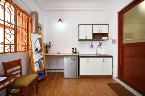 a kitchen with white cabinets and a sink and a table at A&E Guesthouse - Near Bui Vien Walking Street in Ho Chi Minh City