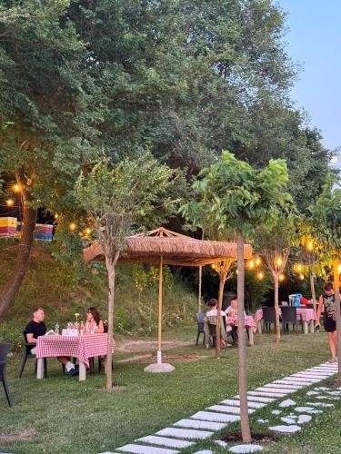 a group of people sitting at tables in a park at Olivia's Hill Resort in Durrës