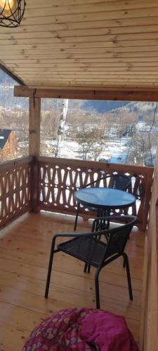 a table and a chair on a wooden balcony at Ioane's Chalet in Mestia