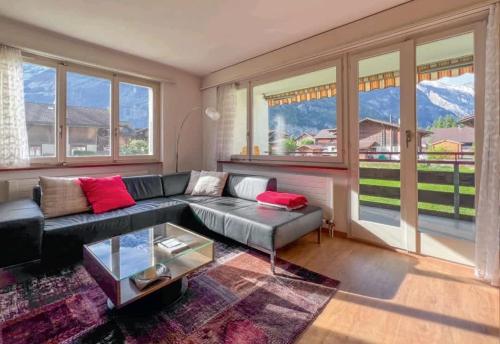 a living room with a couch and a glass table at With Mountain View & Balcony Kitchen Parking in Kandersteg