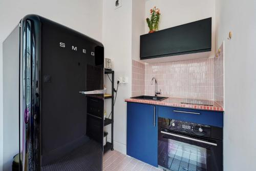 La cuisine est équipée d'un réfrigérateur noir et d'un évier. dans l'établissement Spacious Studio - 2P 43m² - Montorgueil Louvre, à Paris