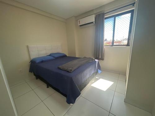 a bedroom with a bed with blue sheets and a window at Na Orla de Petrolina, ar condicionado e elevador in Petrolina