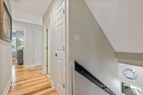 a hallway with white walls and a staircase with wood floors at Oceanside retreat with pool & spa June Weeks Open in Sanderling