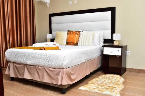 a bedroom with a large bed and a nightstand with a bed sidx sidx sidx at Polka GuestHouse in Tshabong