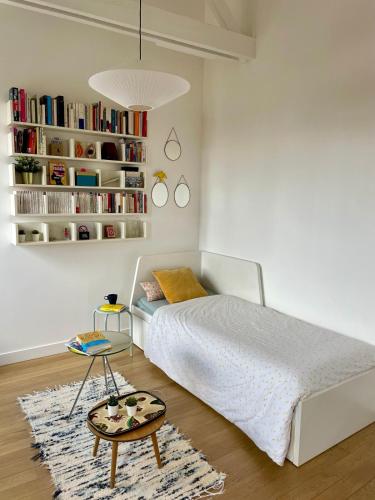 - une chambre avec un lit, une table et une étagère dans l'établissement Cosy-Carnot, à Romainville