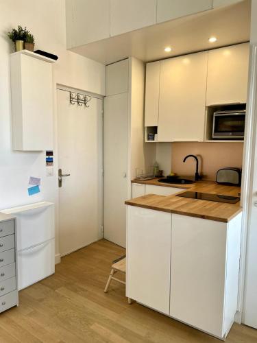 une cuisine avec des armoires blanches et un comptoir dans l'établissement Cosy-Carnot, à Romainville