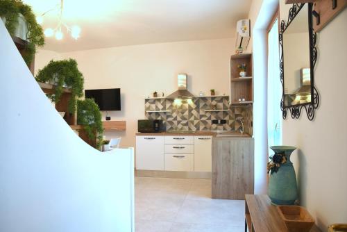 a kitchen with white cabinets and a tv on a wall at Nereidi in Lecce