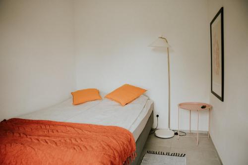 a bedroom with a bed with an orange blanket and a table at Park Hotelik II Piętro in Mielno