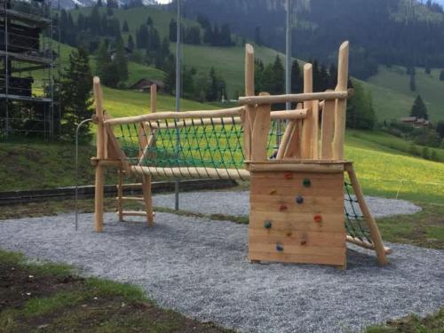 a wooden playground with a climbing frame and a rock at Large Apartment In The Vacation Center Whirlpool in Diemtigen