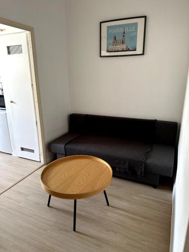 un salon avec un canapé noir et une table dans l'établissement Studio Prado near Velodrome, à Marseille