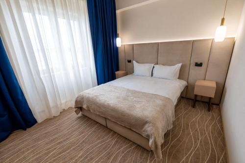a bedroom with a large bed with blue curtains at Sierra in Piteşti