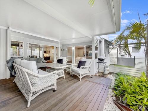 a living room with white wicker chairs and a table at Escape to Emerald Springs - Palm Trees & Pool in Mooloolaba