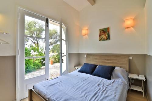une chambre avec un lit et une grande fenêtre dans l'établissement Seaside Villa With Tennis Courts, à Hyères