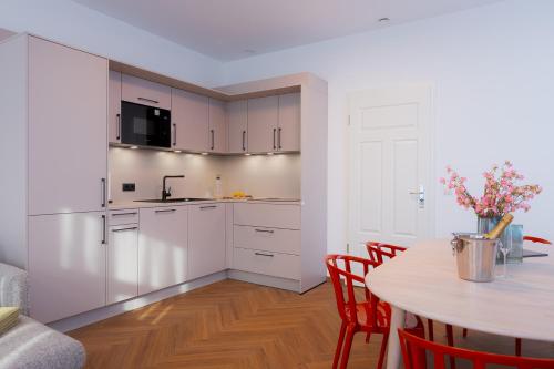a kitchen with white cabinets and a table with chairs at Alpine Apartements Maximilian in Berchtesgaden