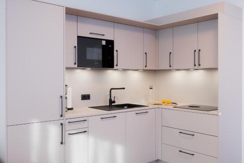 a white kitchen with white cabinets and a sink at Alpine Apartements Maximilian in Berchtesgaden