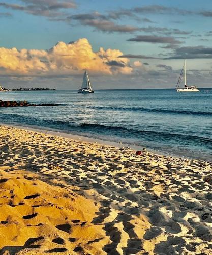 two boats in the water on a sandy beach at Blue Horizon Hotel in Bridgetown