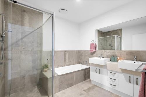 a bathroom with two sinks and a glass shower at Luxury Living with Heated Pool in Birtinya in Kawana Waters