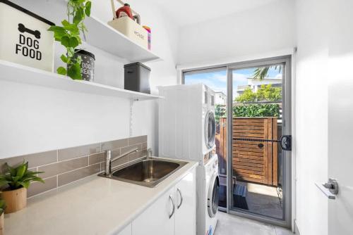 a kitchen with a sink and a refrigerator at Luxury Living with Heated Pool in Birtinya in Kawana Waters