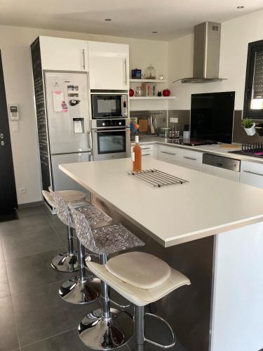 une cuisine avec un comptoir blanc et des tabourets dans l'établissement Villa Moderne, à Castelnau-de-Guers